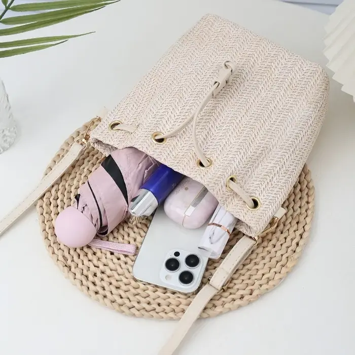 Sac seau bandoulière bohème en paille beige tressée avec cordon de serrage et sangle en cuir réglable