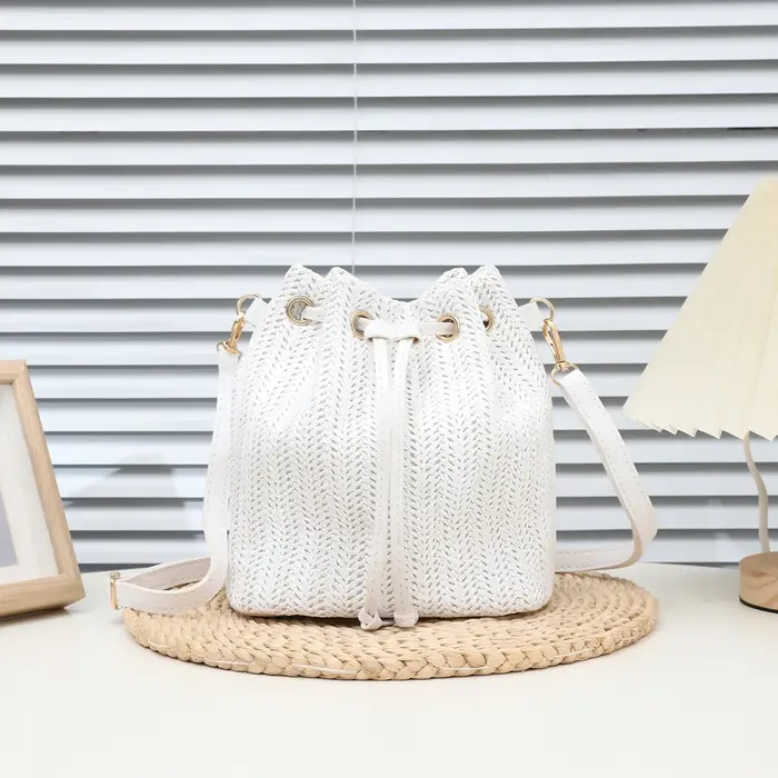 Sac seau bandoulière bohème en paille beige tressée avec cordon de serrage et sangle en cuir réglable